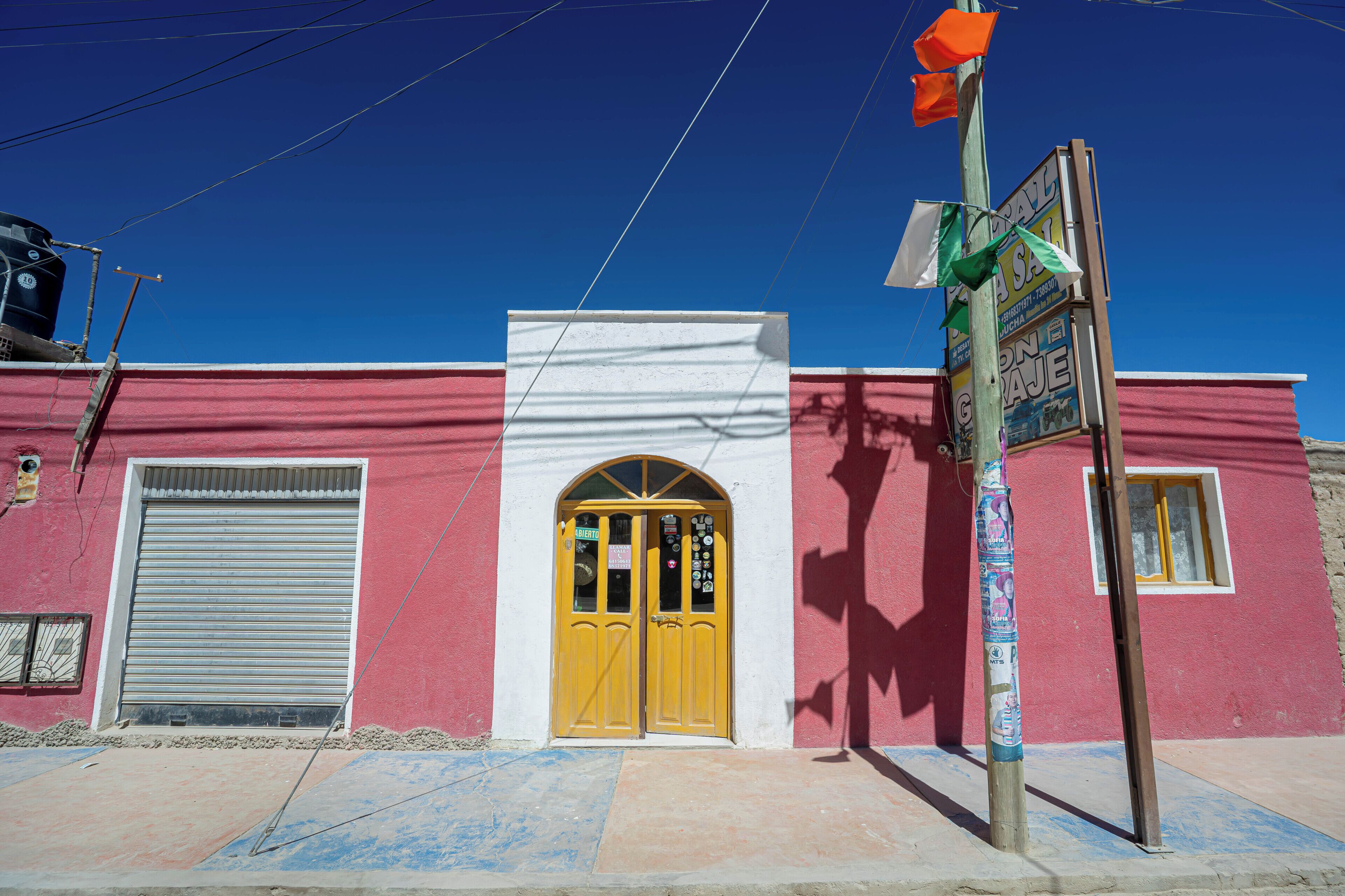 A building with a red facade, a yellow door, and a closed metal shutter.
