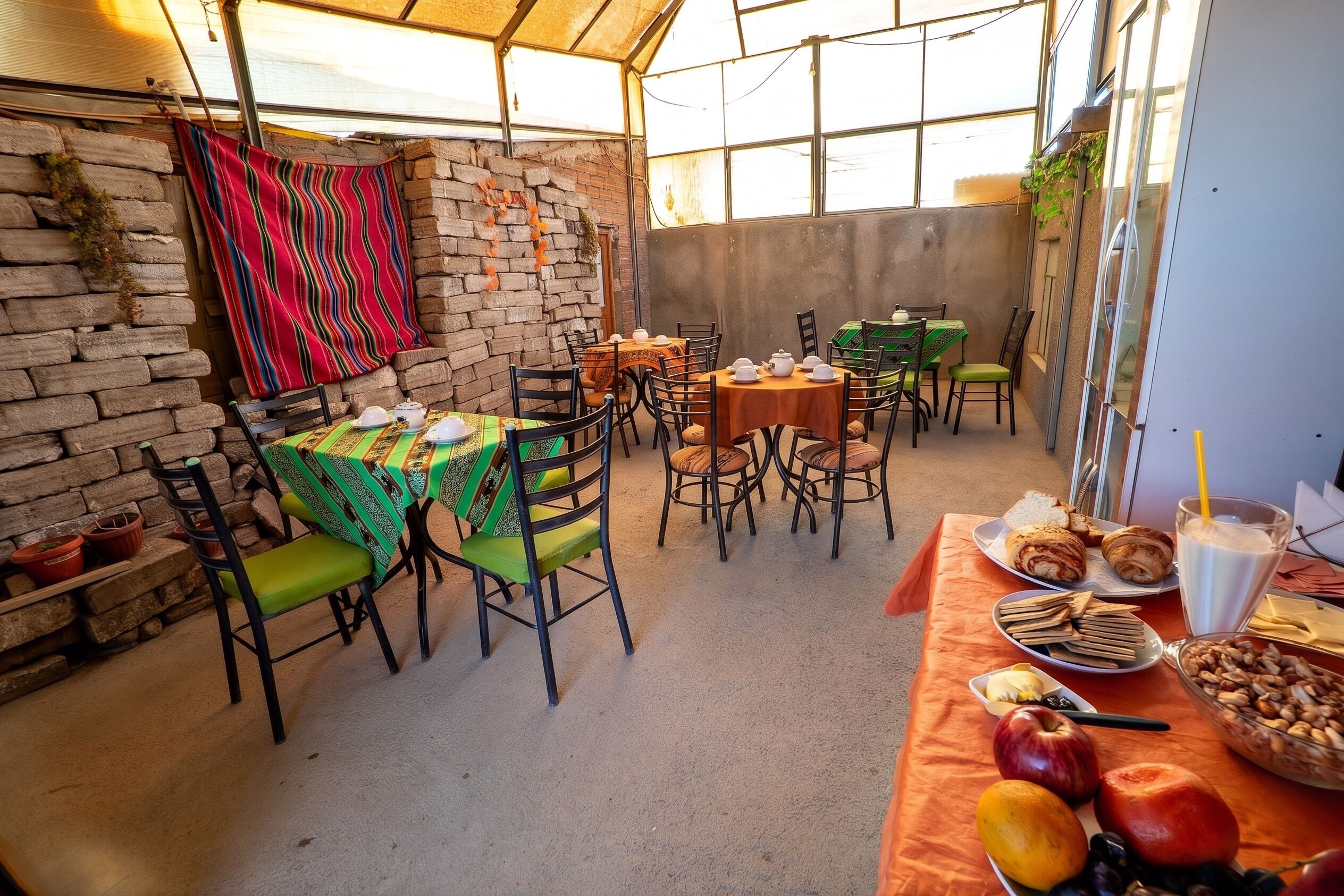An outdoor dining area with brick walls, tables with colorful tablecloths, and chairs.