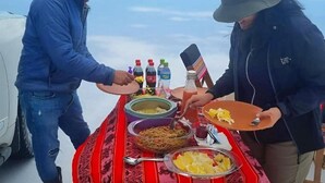 A dining table with food and drinks, a car, and a clear sky in the background.