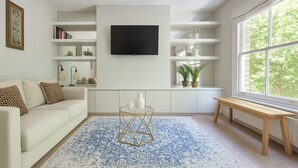 Un salon moderne avec un canapé, une table basse, un téléviseur et une fenêtre donnant sur un beau paysage.