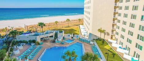 Un hotel con piscina, vista a la playa y varios pisos.