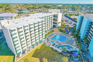 A multi-story hotel with a rooftop pool, outdoor seating, and a view of the surrounding area. - Beachside Studio: Updated, Ground Floor near Tootsie's wPool, Patio, Free Chairs (Panama City Beach)