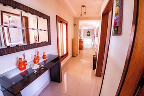 A hallway with a glass display case, wooden doors, and a ceiling fan. - House with heated pool - Incredible View - Ilhabela - Beach Tennis Court. (SÃO SEBASTIÃO)