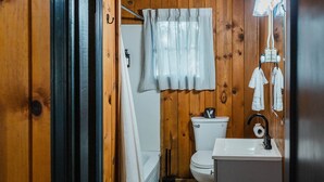 A wooden-paneled bathroom with a toilet, sink, and shower curtain. - 2 BR 2 BA San Juan Mountain Cabin (Archuleta County)