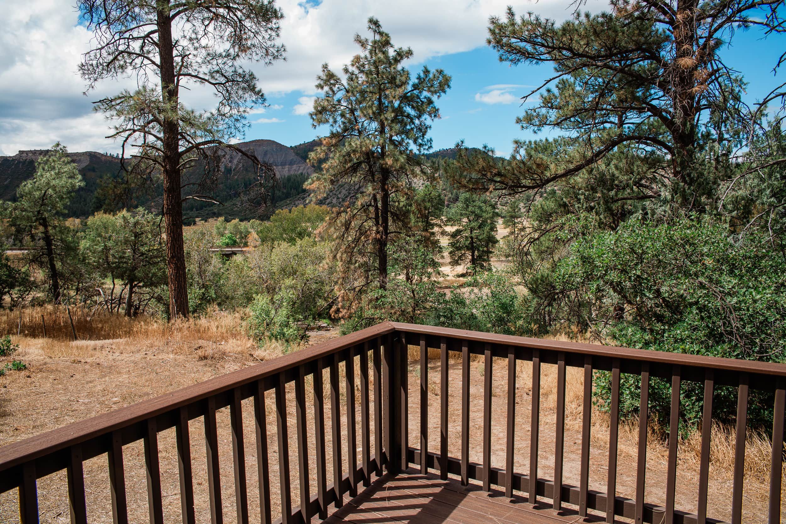 A wooden deck with a view of a mountainous landscape and dense forest.