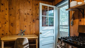 Interior de madeira com uma mesa de jantar, uma cadeira, um fogão e uma porta com janela.