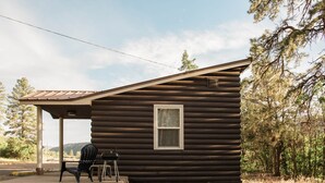 Una baita di legno con un portico, un tavolo e una sedia.