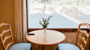 Un tavolo rotondo in legno con due sedie imbottite blu, un vaso con fiori e un telecomando sul tavolo.