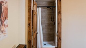 Una camera da letto con una testiera in legno, un letto con biancheria da letto bianca, una panca in legno e un tavolino con fiori.