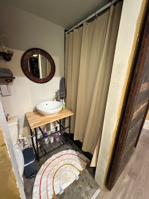 Een badkamer met een witte wastafel, een spiegel, een douchegordijn en een handdoekhouder.