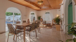 A spacious dining area with a wooden ceiling, a large table, and patterned chairs.