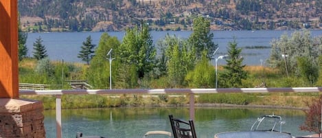 A lakeside patio with outdoor seating and a view of a lake and forested hills.