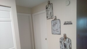 Ein Flur mit einer weißen Tür, gefliestem Boden und drei an der Wand befestigten Dekorationen mit Text.