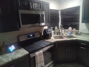 A kitchen with a microwave, oven, and coffee maker.