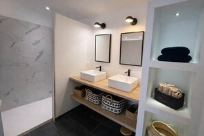 Ein modernes Badezimmer mit zwei Waschbecken, einem Spiegel und Regalen mit Körben.