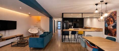 A modern living room with a sofa, TV, and dining area with chairs and a table.