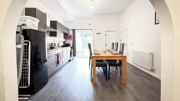 A modern kitchen with a dining area, including a table with chairs, a washing machine, and a radiator.