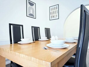 A dining table with chairs, plates, bowls, and cutlery. There are framed pictures on the wall and a sign that reads 'GOOD VIBES ONLY'. - Comfortable Single Room in Wigan House Share (Wigan)