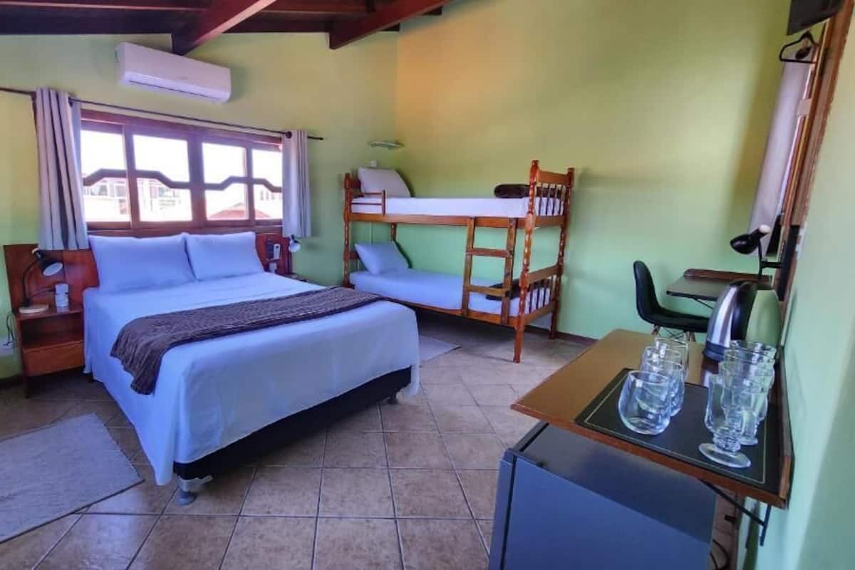 Una habitación con cama, escritorio, silla y literas.