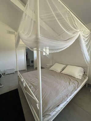 A single bed with a canopy, a bedside table, and a radiator. - Hossegor – Villa between the lake and the ocean, within walking distance of the beach – Sleeps 6 – Wi-Fi and air conditioning (SOORTS HOSSEGOR)