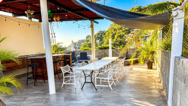 An outdoor patio with a dining table, chairs, and a bar area. - Hidden Gem 1BR Near Romantic Zone (Puerto Vallarta)
