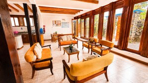 A spacious living area with wooden furniture, large windows, and a kitchen in the background. - Modern, Spacious House with a Cozy Atmosphere and an Excellent Location (Puerto Ayora)