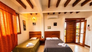 A room with two beds, a wooden ceiling, an air conditioning unit, and a door leading outside. - Modern, Spacious House with a Cozy Atmosphere and an Excellent Location (Puerto Ayora)