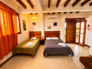 A room with two beds, a wooden ceiling, an air conditioning unit, and a door leading outside. - Modern, Spacious House with a Cozy Atmosphere and an Excellent Location (Puerto Ayora)