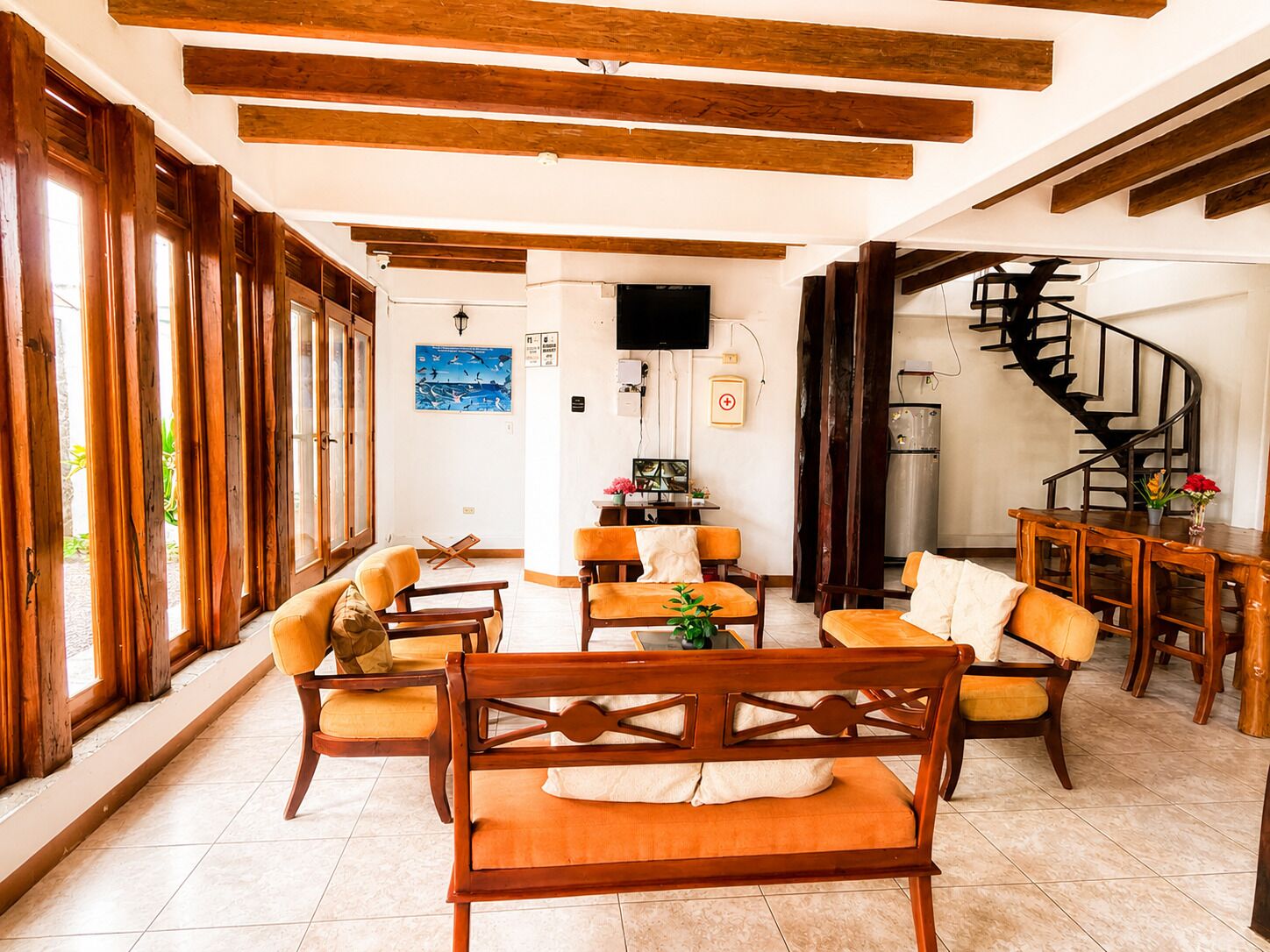 A spacious living area with wooden furniture, a flat-screen TV, a staircase, and a view of the outdoors.