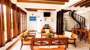 A spacious living area with wooden furniture, a flat-screen TV, a staircase, and a view of the outdoors. - Modern, Spacious House with a Cozy Atmosphere and an Excellent Location (Puerto Ayora)