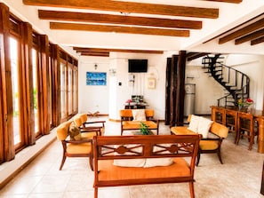 A spacious living area with wooden furniture, a flat-screen TV, a staircase, and a view of the outdoors. - Modern, Spacious House with a Cozy Atmosphere and an Excellent Location (Puerto Ayora)