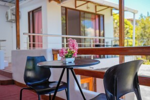 A balcony with a table and chairs, a potted plant, and a building with large windows and a balcony railing. - Modern, Spacious House with a Cozy Atmosphere and an Excellent Location (Puerto Ayora)