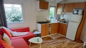 Ett kompakt bostadsutrymme med ett litet kök, en soffa, ett litet bord och en stol.