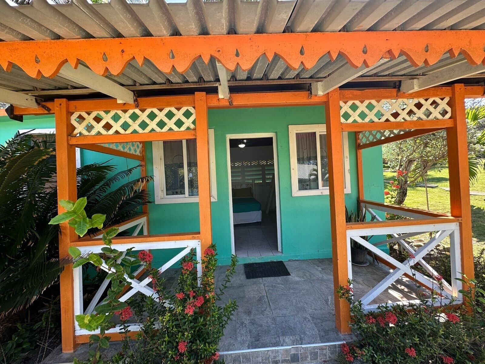 A covered entrance with a green door, white lattice, and orange accents.