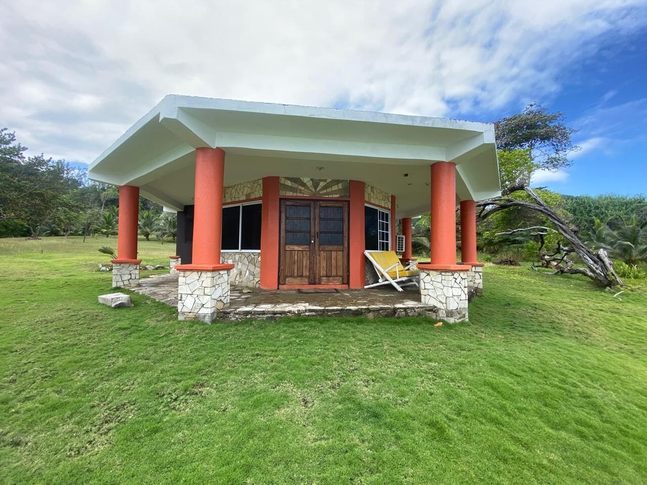 Una casa con porche, puerta de madera y base de piedra.