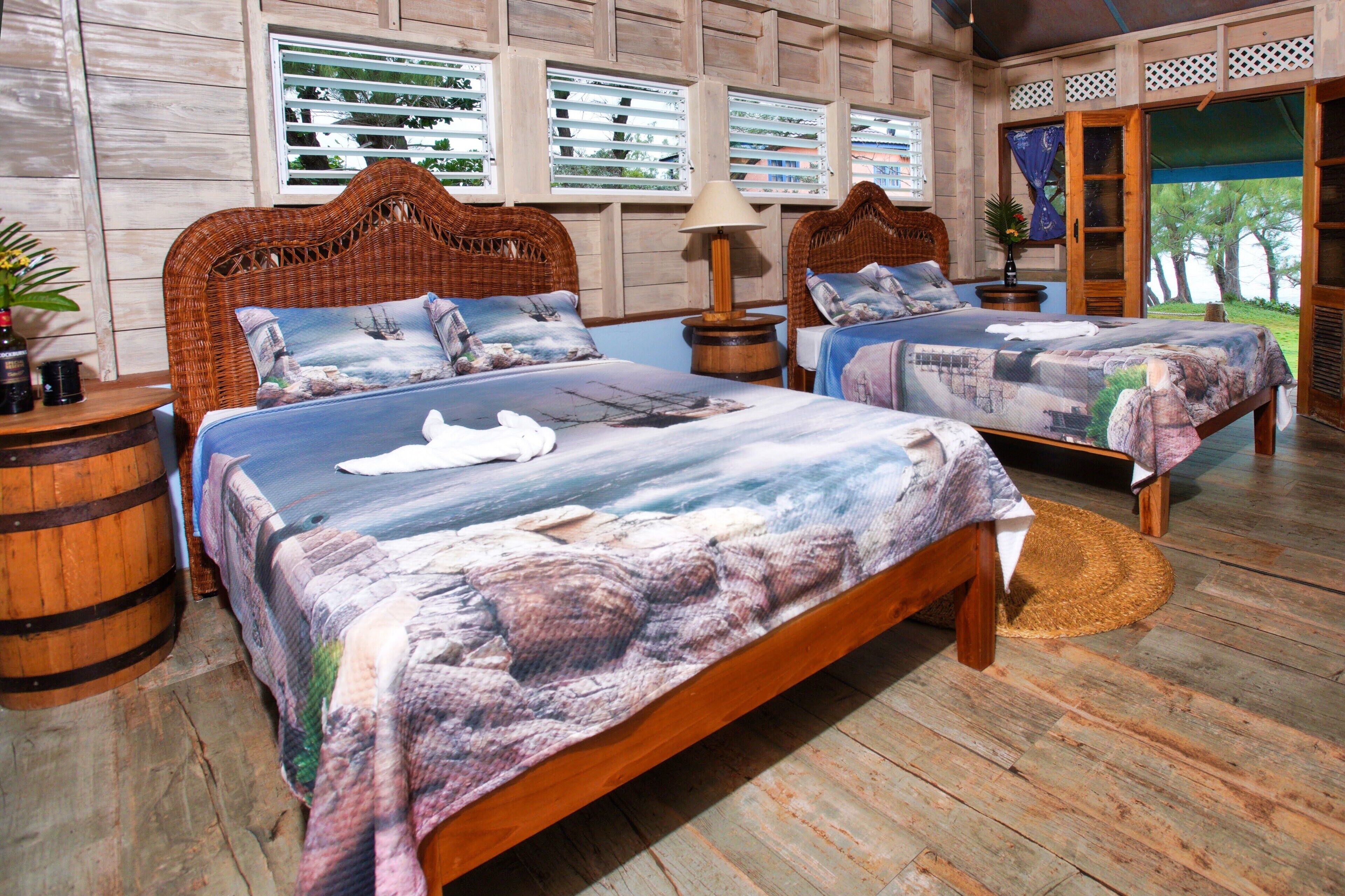A room with two wooden beds, a wicker headboard, a wooden floor, and a view through the window.