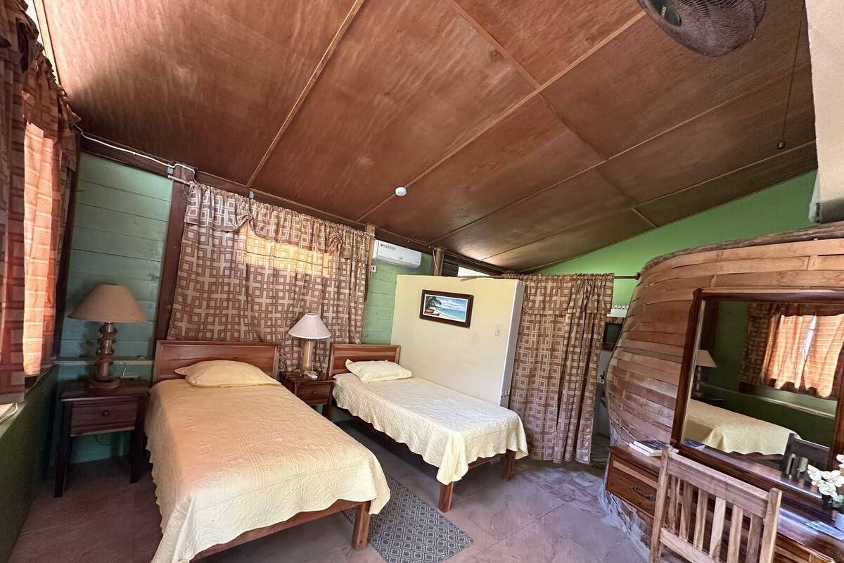 A room with two beds, a wooden desk, a mirror, and a small rug.