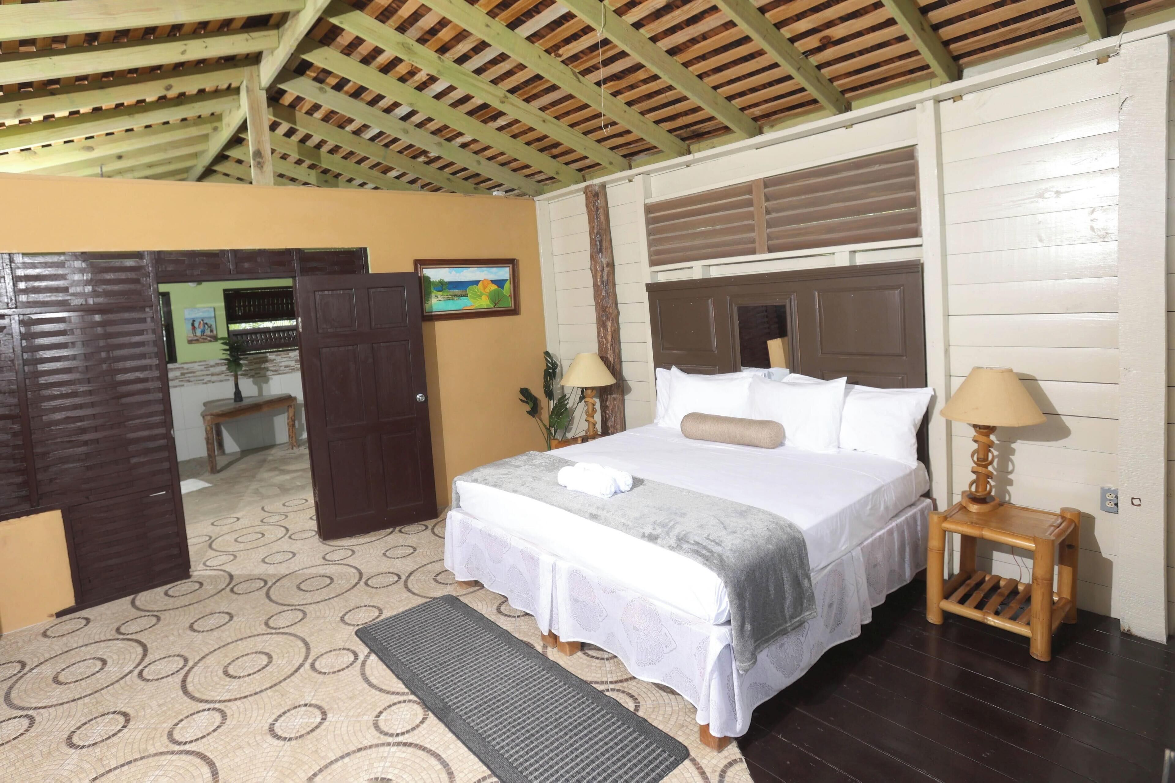 A bedroom with a bed, bedside tables, a door, a wall with a picture, and a patterned floor.