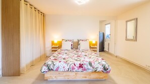 A bedroom with a bed, two bedside lamps, a window, a mirror, and a door. - LES CIGALES - TRESSERVE (TRESSERVE)