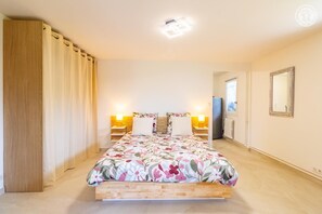 Ein Schlafzimmer mit einem Bett, zwei Nachttischlampen, einem Fenster, einem Spiegel und einer Tür.