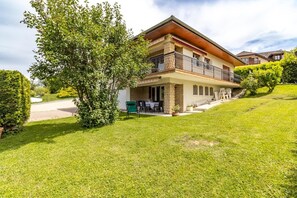Ein zweigeschossiges Haus mit Balkon, gepflasterter Auffahrt und einem gepflegten Rasen.