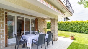 An outdoor patio with a table set for six, surrounded by wicker chairs, against a stone wall. - LES CIGALES - TRESSERVE (TRESSERVE)
