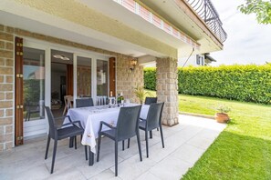 Eine Terrassengruppe im Freien mit einem Tisch für sechs Personen, umgeben von Korbstühlen, an einer Steinwand.