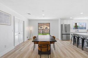 A modern kitchen with a dining table, chairs, and a refrigerator.