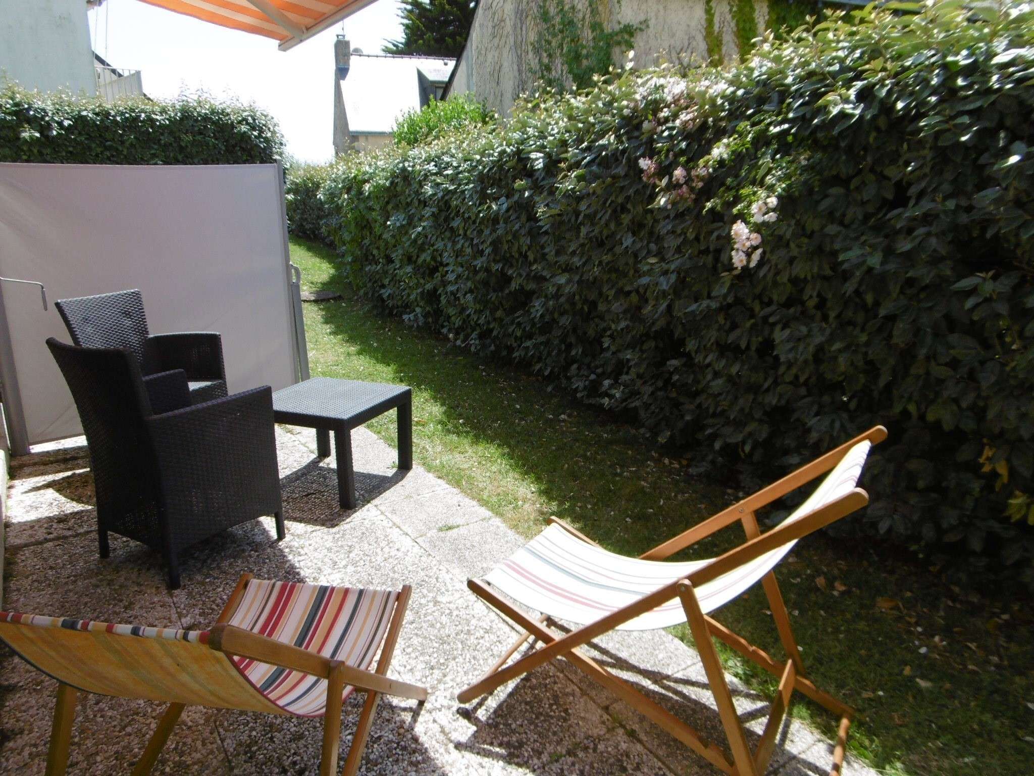 Un espacio de estar al aire libre con mobiliario de mimbre y una hamaca.
