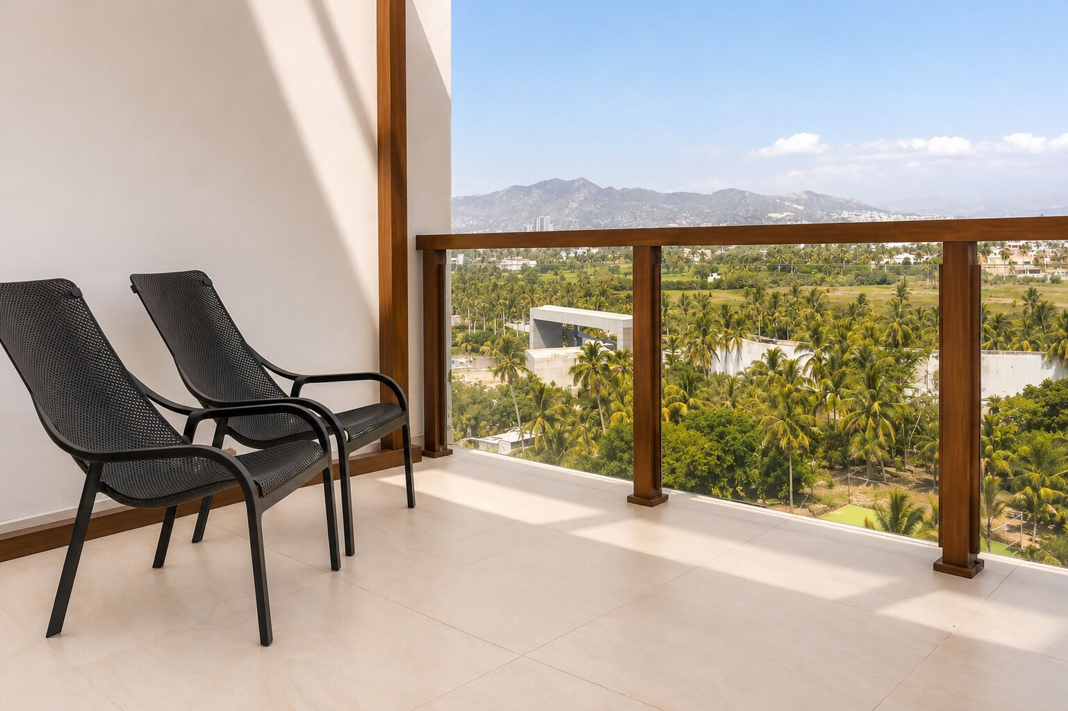 Un balcón con dos sillas y vistas a un paisaje con palmeras y edificios.