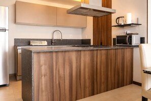 Eine moderne Küche mit Kochinsel, Edelstahlgeräten und einer Holz-Spritzschutzwand.