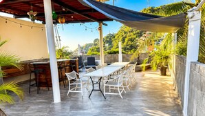 An outdoor patio with a dining table, chairs, and a bar area. - Charming Studio Near Romantic Zone (Puerto Vallarta)