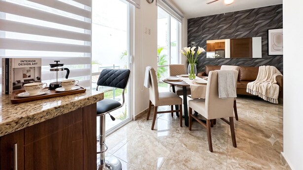 A modern kitchen with a marble countertop, a dining area with a table and chairs, a ceiling fan, and a living area with a sofa and a fireplace. - Charming Studio Near Romantic Zone (Puerto Vallarta)