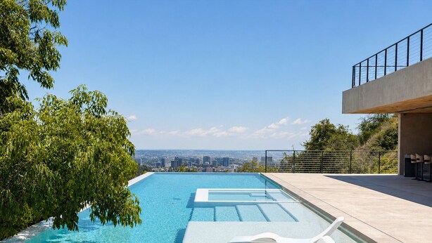 Una piscina infinita moderna con agua azul cristalina, rodeada de exuberante vegetación y vistas a la ciudad.